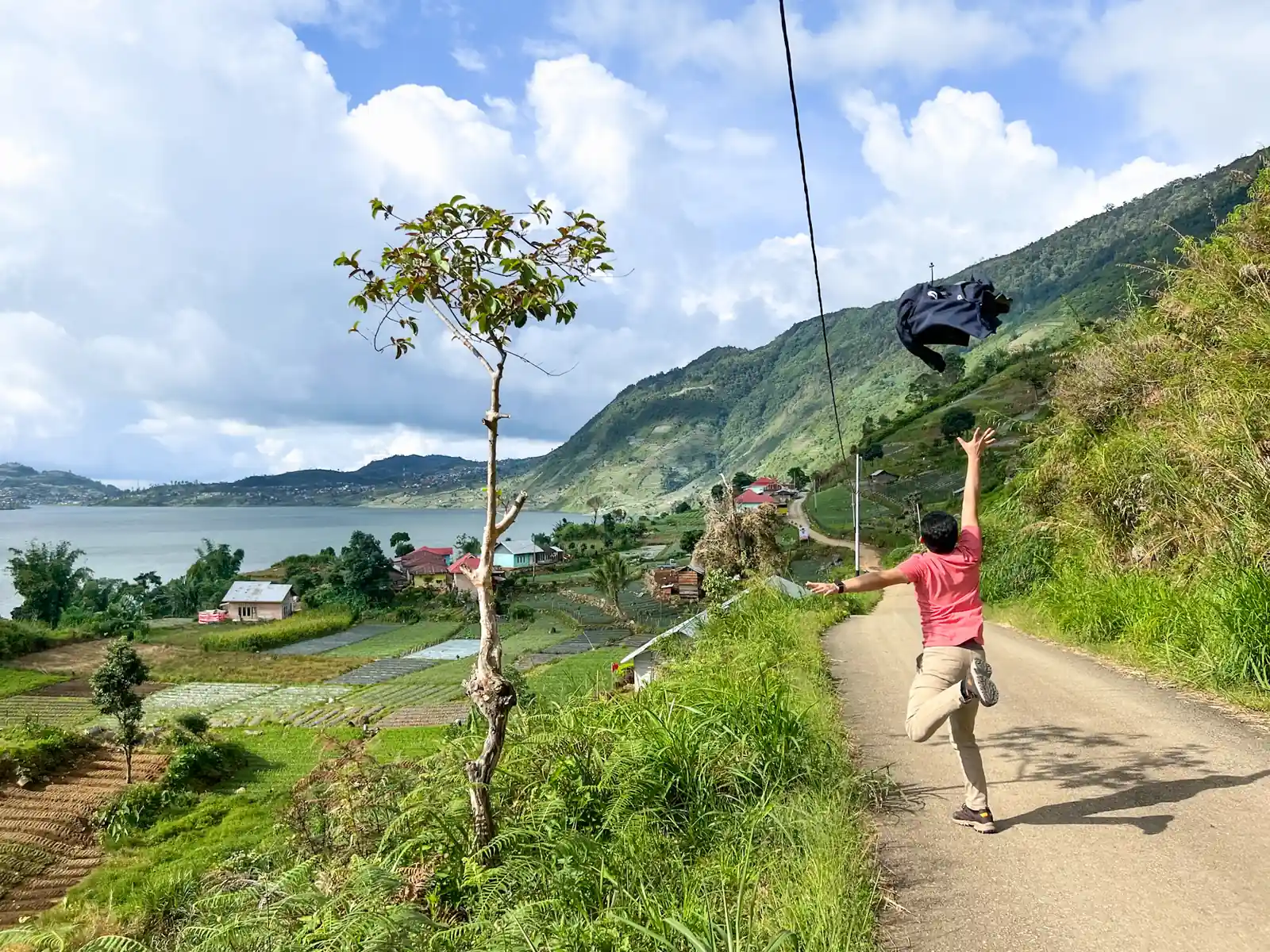 Traveler on a rope swing high above a green valley and lake